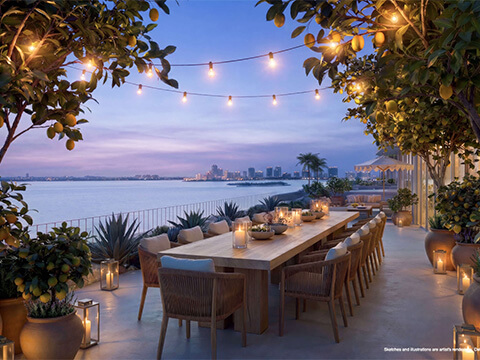 Waterfront dining terrace at Continuum 12000 North Miami with illuminated lemon trees and evening bay views