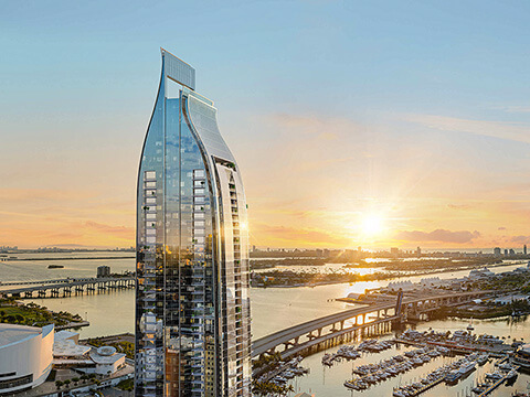 Sunset waterfront view of Delano Residences Miami tower overlooking the bay and marina