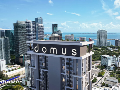 Rooftop view with Domus Brickell Center signage overlooking the Brickell skyline and Biscayne Bay