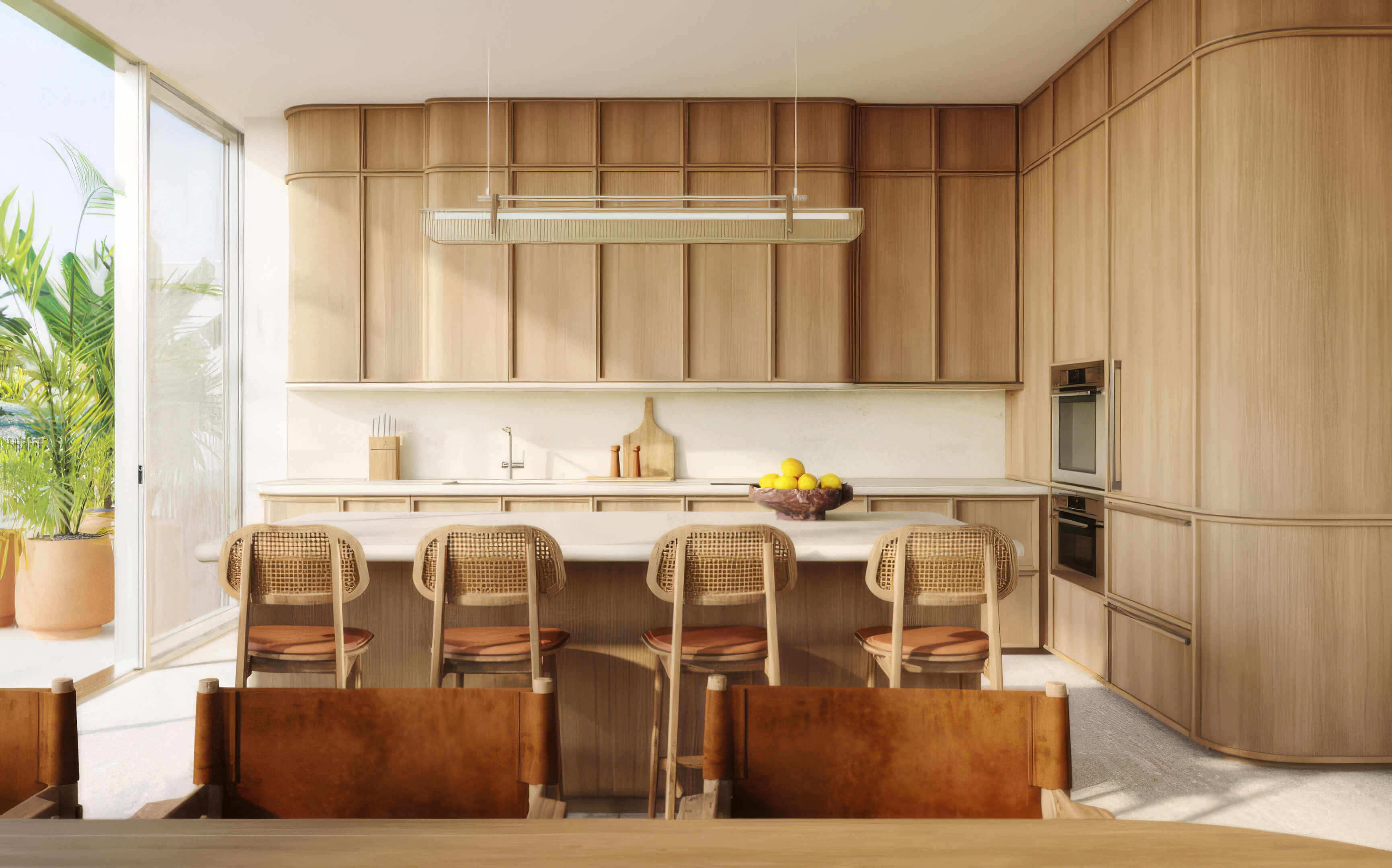 Kitchen with wood cabinetry, a pale stone island, and four woven bar stools at Fouquet’s Hotel & Residences
