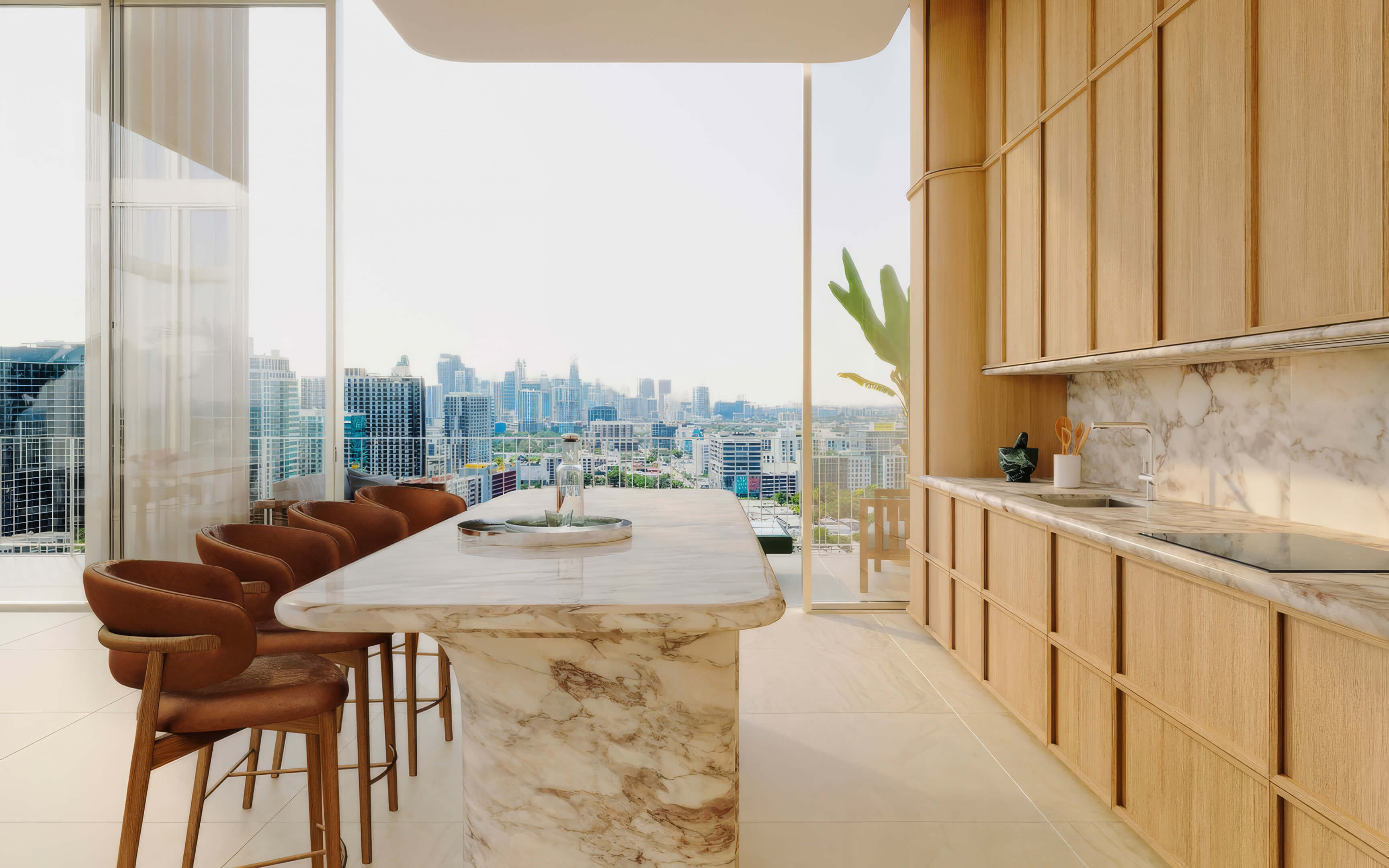 Kitchen with a veined stone island, brown bar stools, and a city view at Fouquet’s Hotel & Residences