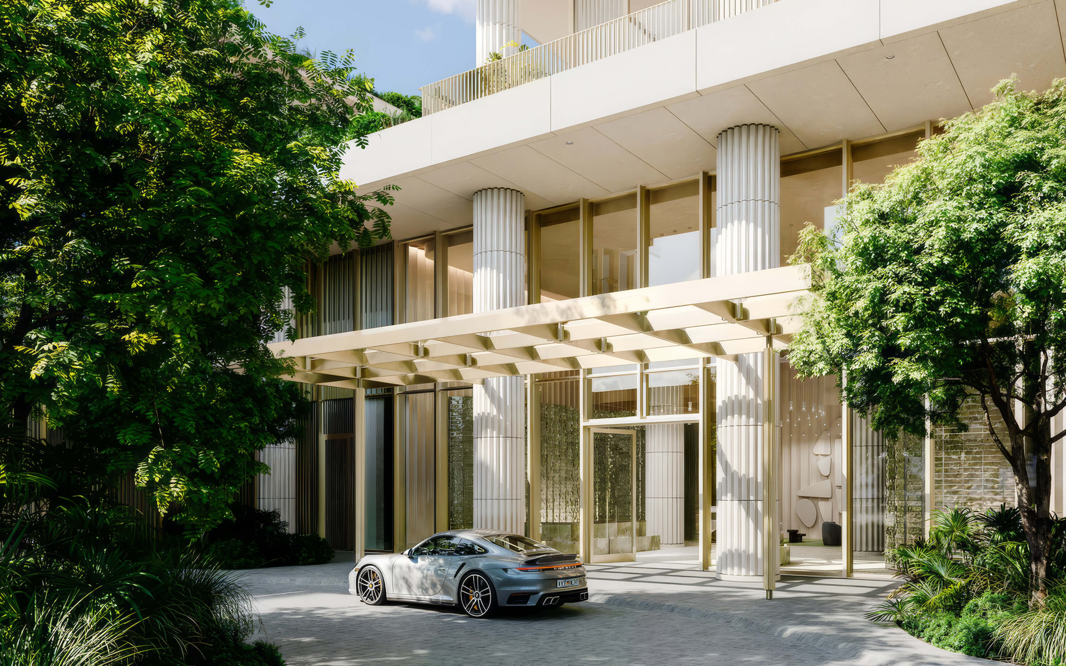 Landscaped arrival driveway with a parked car beneath the entrance canopy at Fouquet’s Hotel & Residences