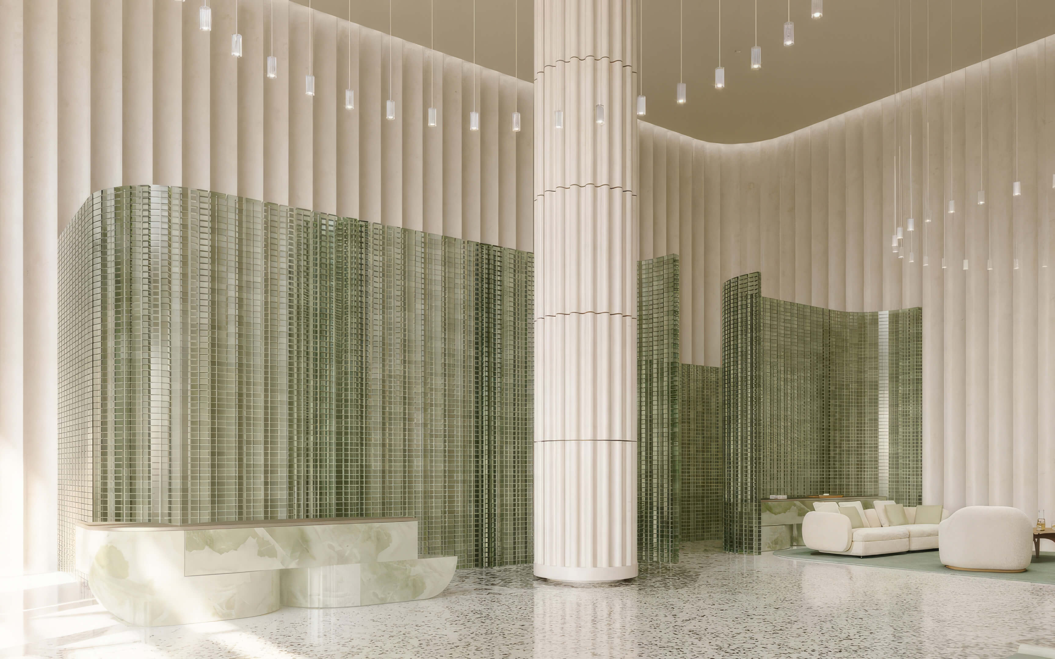 Lobby with a curved green tile reception desk, fluted columns, and pendant lights at Fouquet’s Hotel & Residences