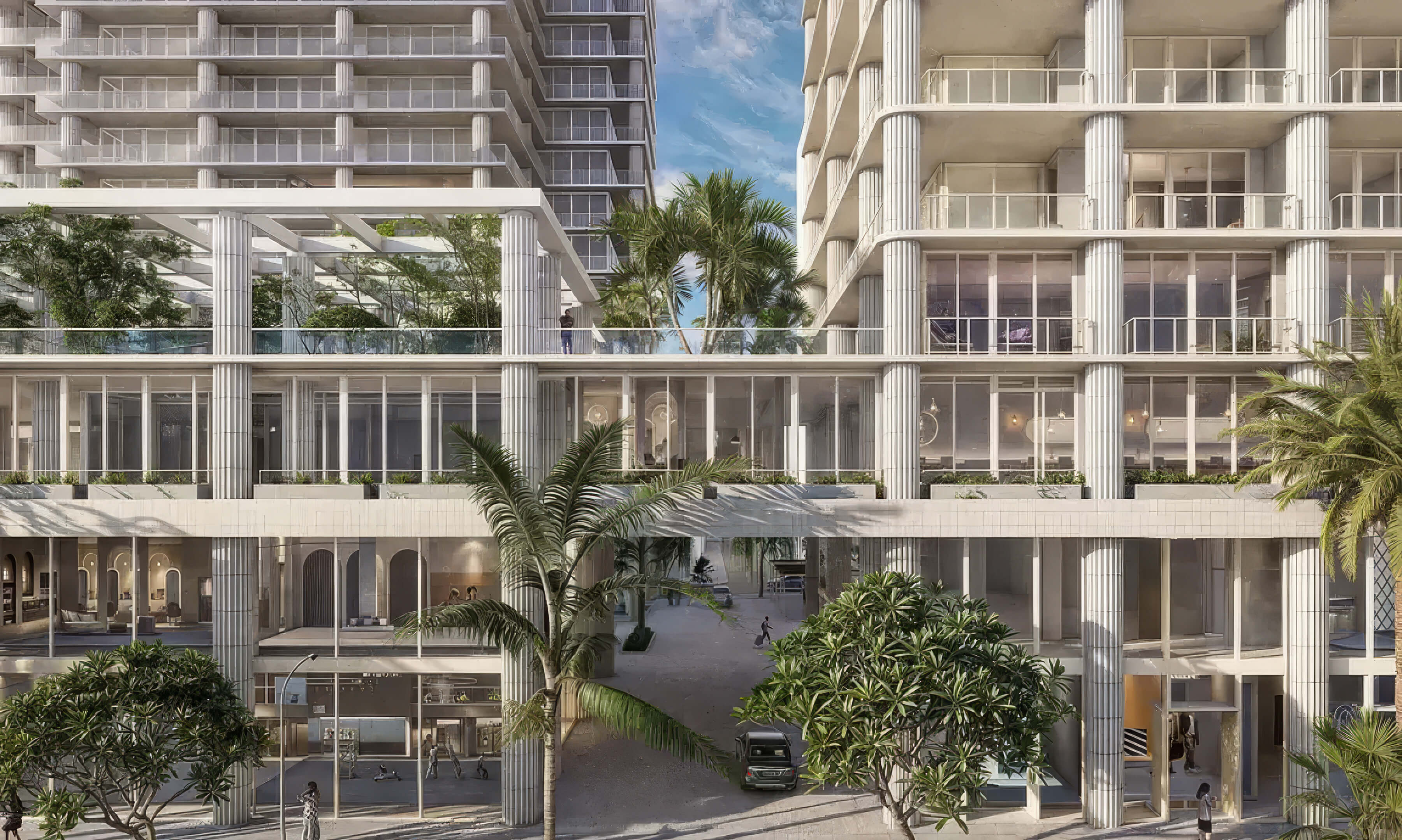 Landscaped podium courtyard between towers with glass walls and palm trees at Fouquet’s Hotel & Residences