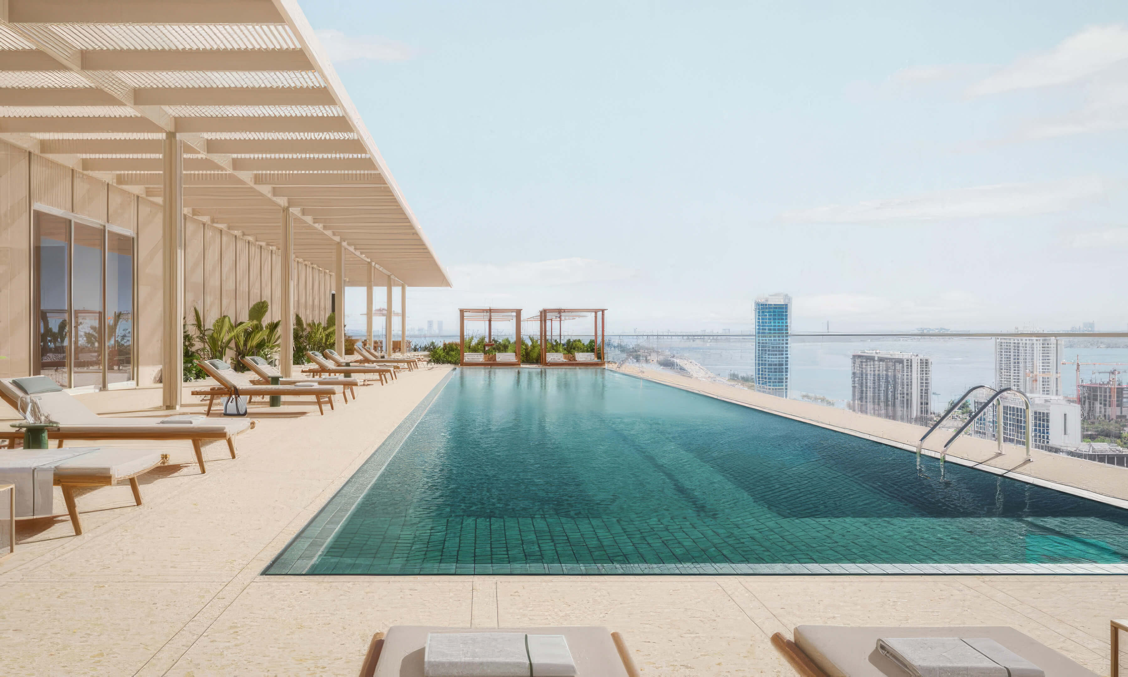 Rooftop lap pool with sun loungers, cabanas, and views over the city and bay at Fouquet’s Hotel & Residences