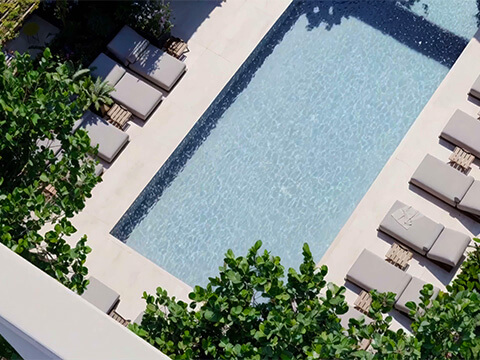 Top-down aerial view of the rooftop pool at HQ Residences Edgewater with sun loungers and lush landscaping