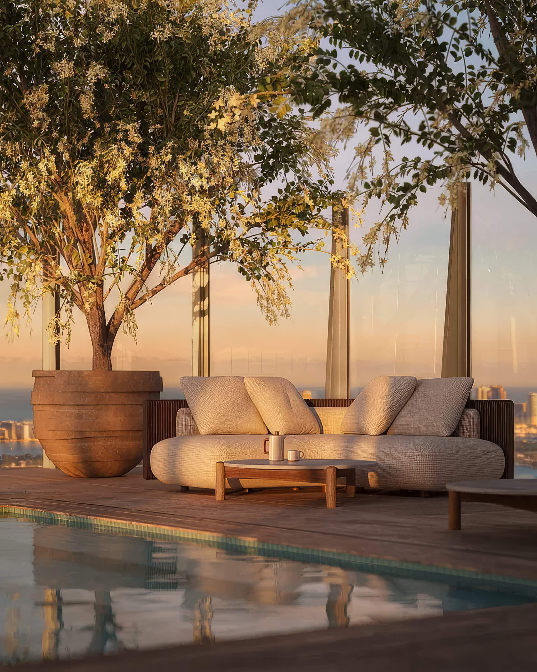 Poolside sofa at Lilli Miami Edgewater beneath a potted tree beside the glass terrace railing