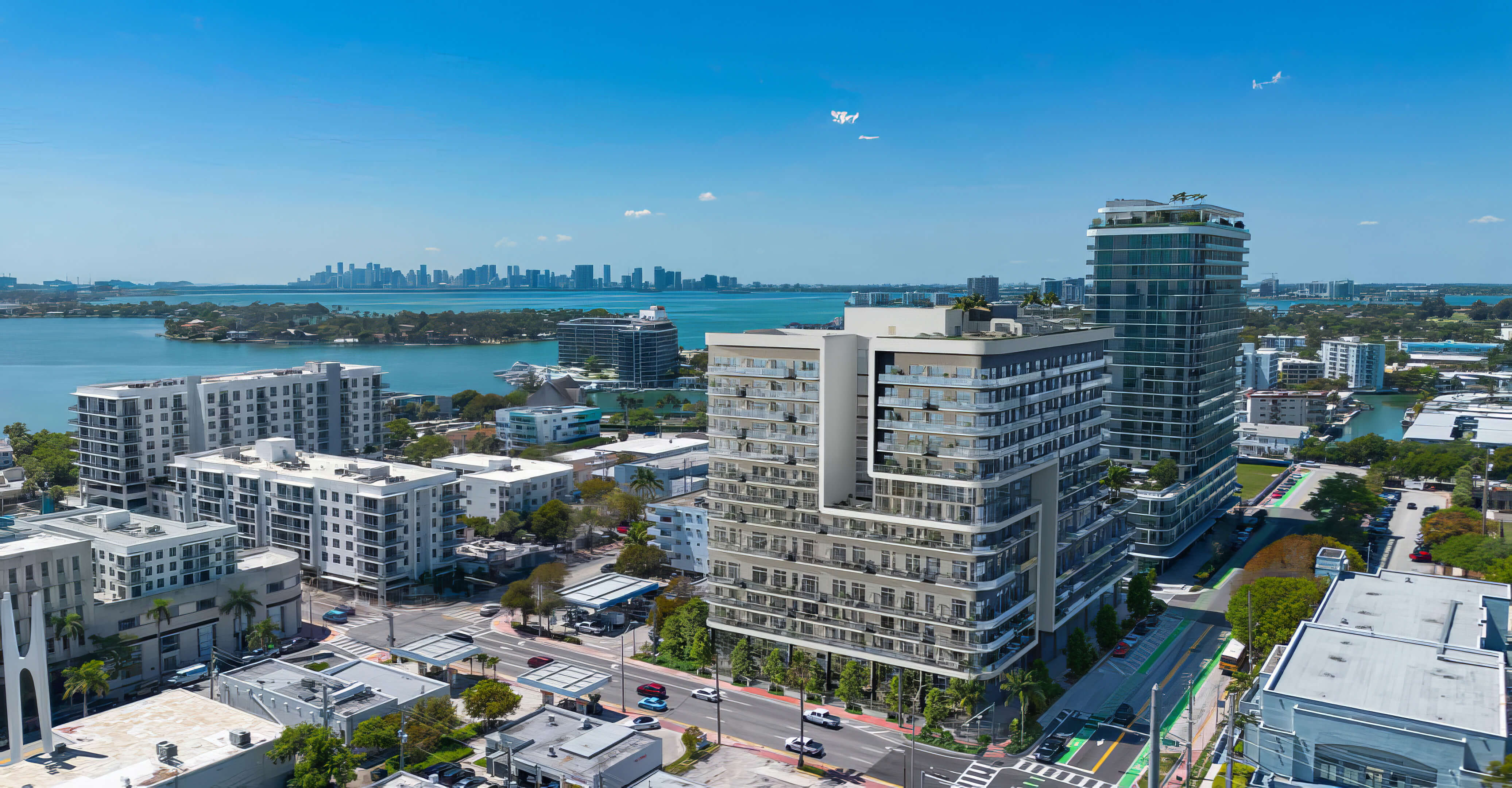 Neighborhood aerial view of NoBe Parc Miami Beach with Biscayne Bay, city skyline and nearby coastal buildings
