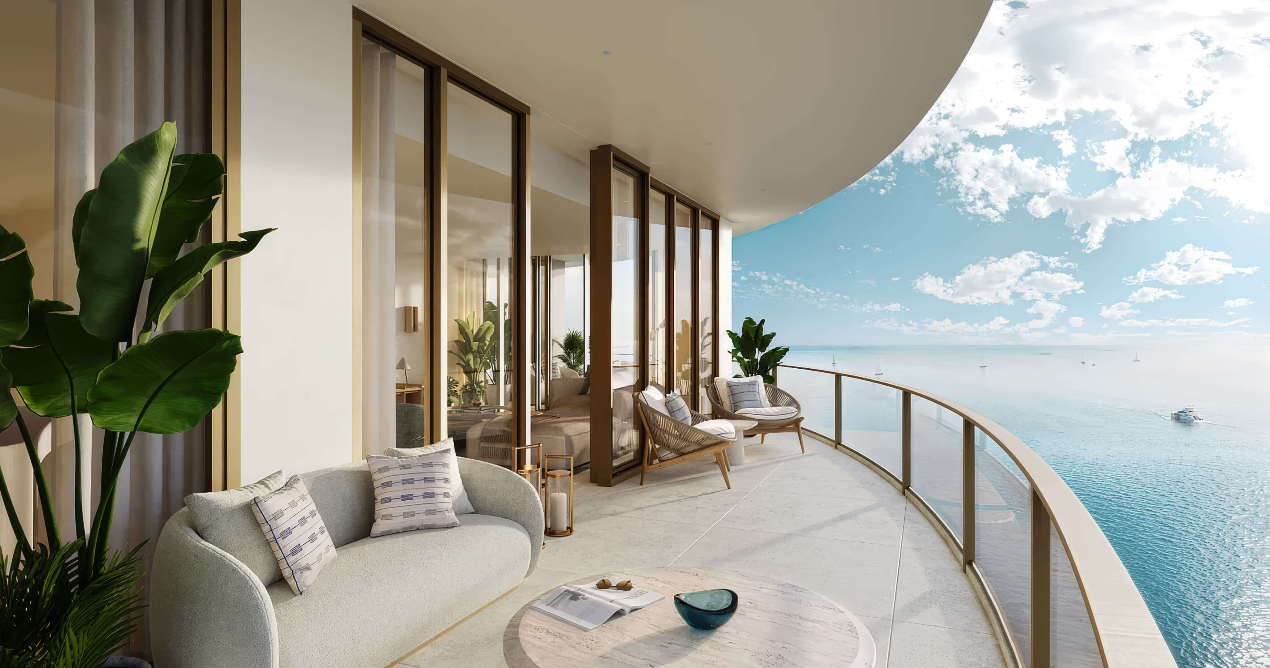 Curved balcony with a sofa, lounge chairs and glass railings overlooking the ocean at St Regis Residences Bahia Mar
