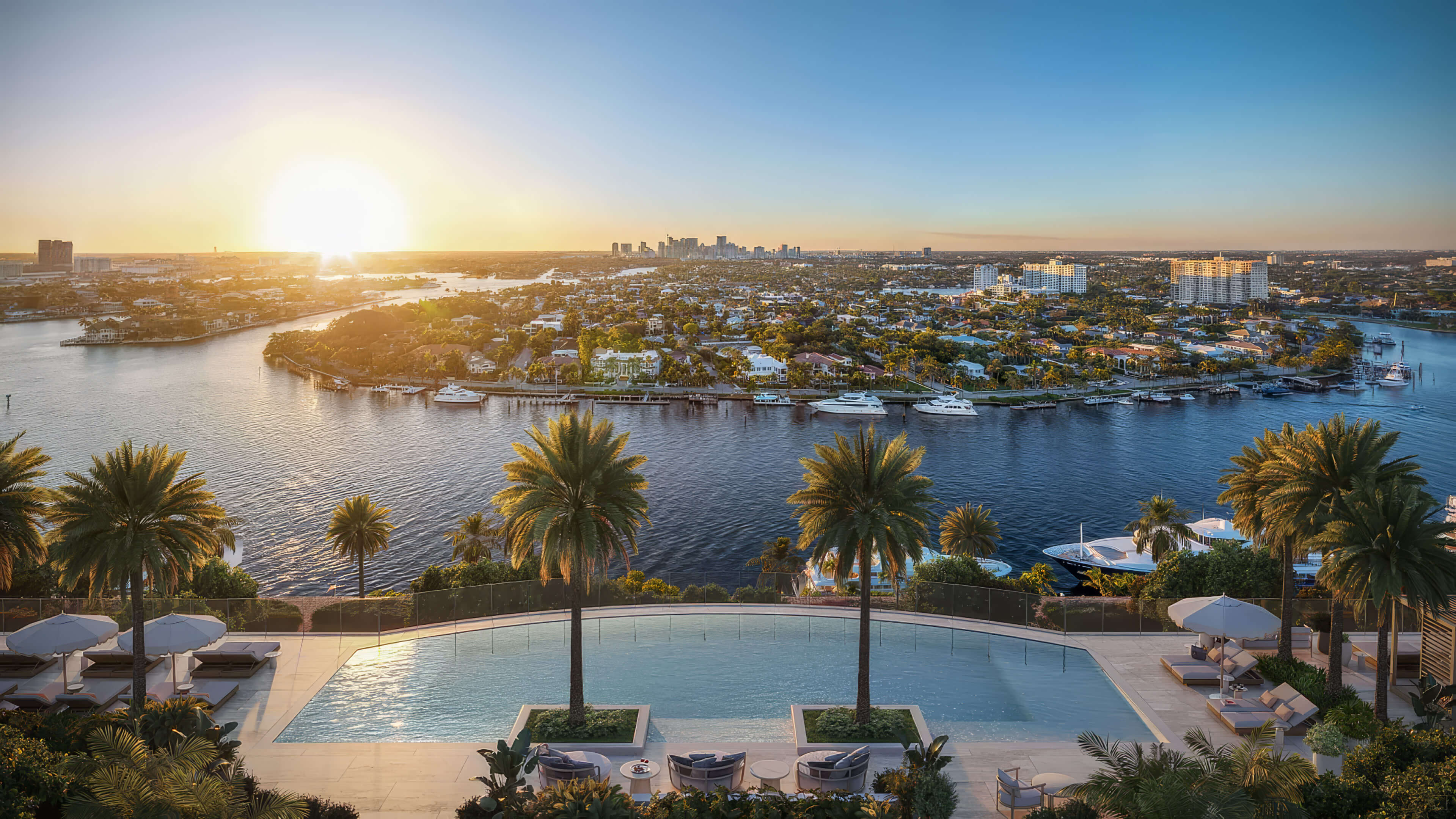Elevated outdoor pool overlooking palm trees and a waterway at sunset at St Regis Residences Bahia Mar