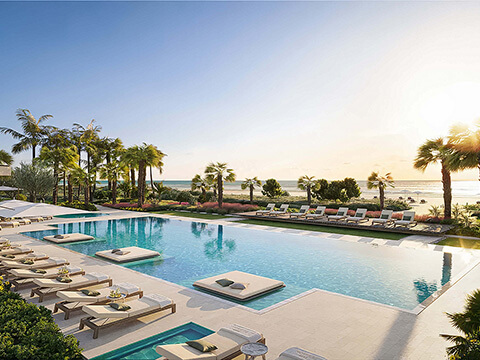 Oceanfront resort pool at The Perigon Miami Beach with luxury loungers, palm trees, beachfront landscaping, and sunset ocean views